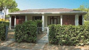 Una casa a due piani con tetto in tegole, cancello e giardino curato.