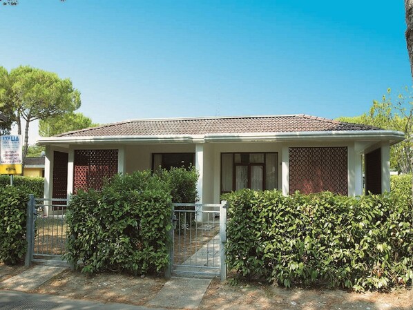 A two-story house with a tiled roof, a gated entrance, and a well-maintained garden.