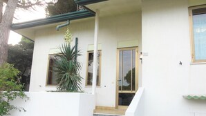 Ein weißes Gebäude mit Veranda, Treppe und einem Fenster mit Tür.