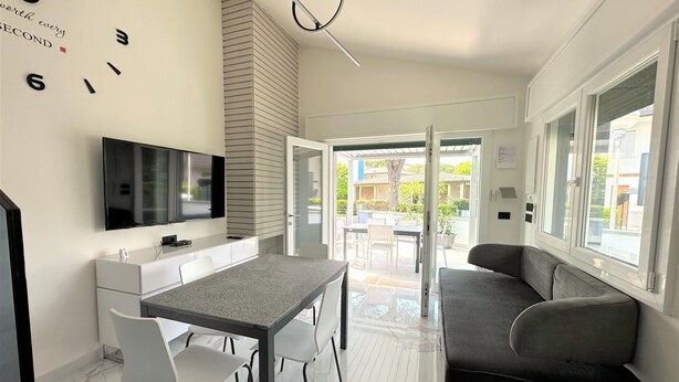 Una cocina moderna con televisión, una mesa de comedor con sillas y un sofá.