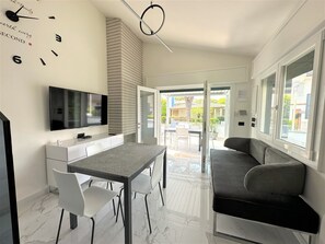 A modern kitchen with a TV, a dining table with chairs, and a sofa. - Villa Wanda (San Michele al Tagliamento)
