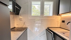 Una cocina moderna con encimeras de mármol, electrodomésticos integrados y un ventanal que proporciona luz natural.