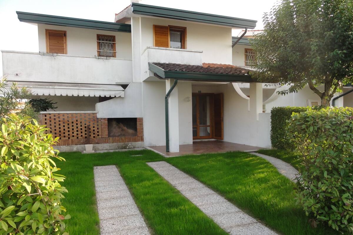 A two-story house with a tiled roof, a brick fireplace, and a paved driveway.
