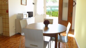 Un comedor con una mesa redonda, sillas, un microondas y una pequeña planta en maceta.