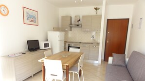 Una cocina compacta con comedor, un sofá y una televisión.