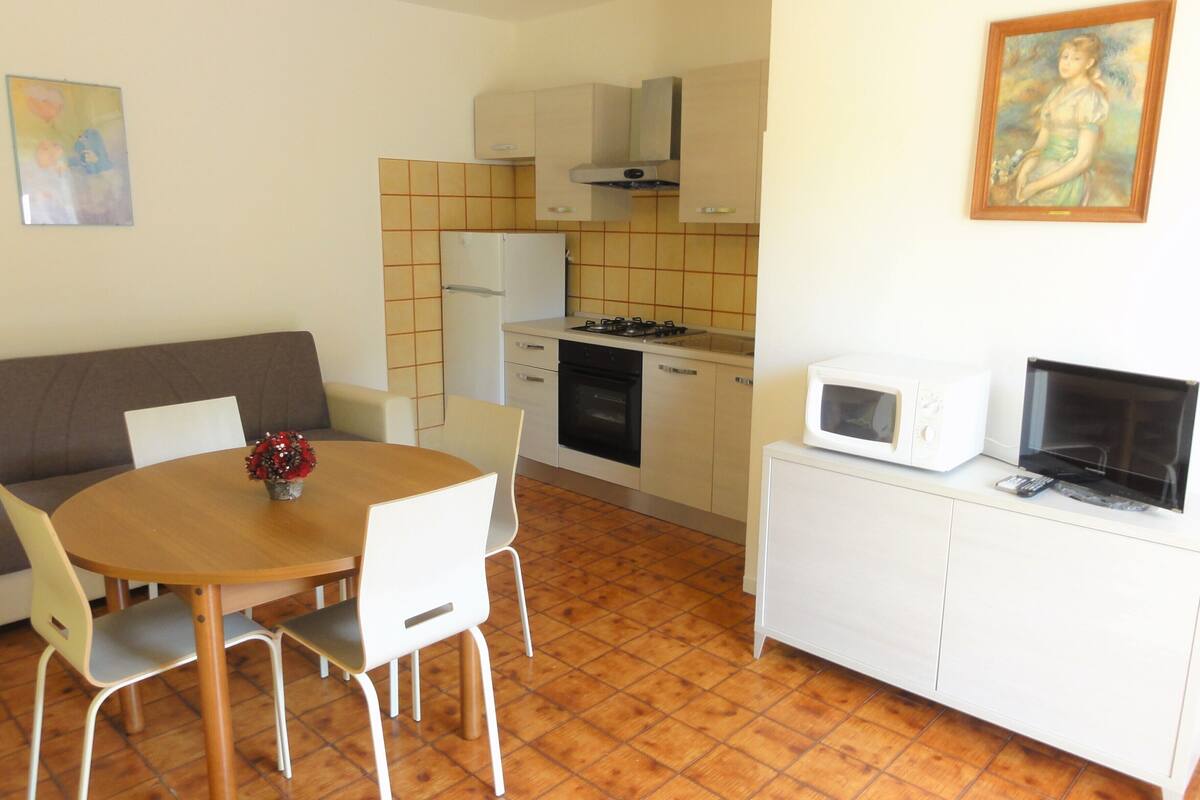 Una cocina funcional con comedor, un sofá y un cuadro en la pared.