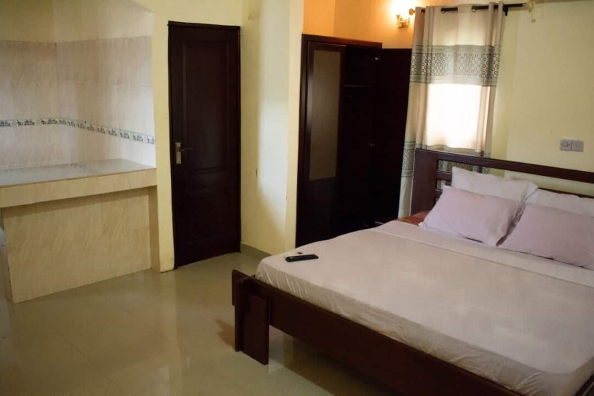 A bedroom with a bed, a wooden bench, a wardrobe, and a mirror.