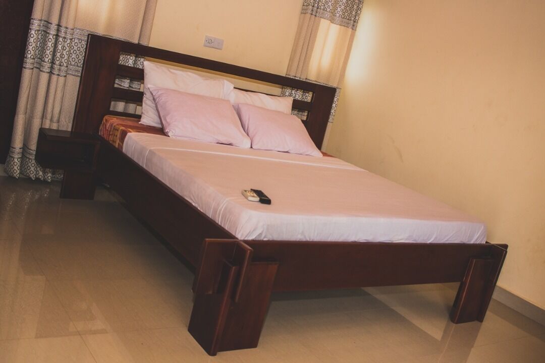 A single bed with a wooden frame, a white mattress, and two pillows.