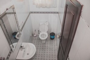 A small bathroom with a toilet, sink, and a mirror.