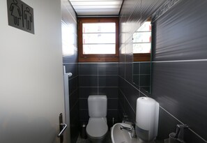 A small, modern bathroom with a toilet, sink, and hand dryer. - La Maison de la Montagne (Ollon)