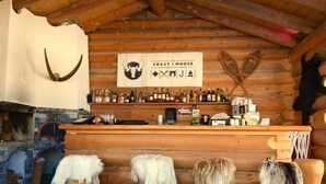 A rustic bar area with wooden walls, a mounted moose head, and a variety of bottles. - La Maison de la Montagne (Ollon)