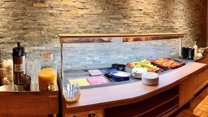 A buffet with various food items, a juice dispenser, and condiments. - La Maison de la Montagne (Ollon)