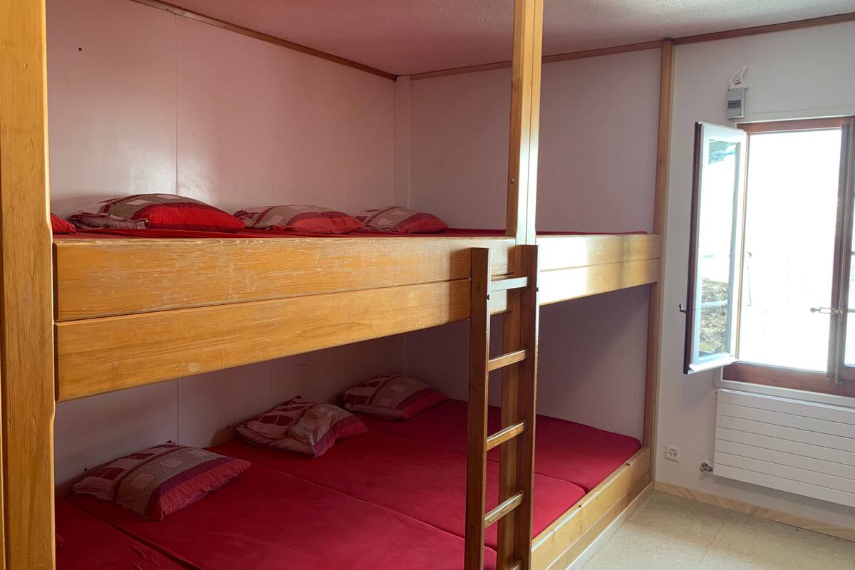 Dormitorio con literas, una ventana y un radiador.