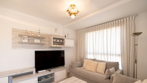 Una sala de estar con una televisión de pantalla plana, un sofá, una mesa de centro y un candelabro.
