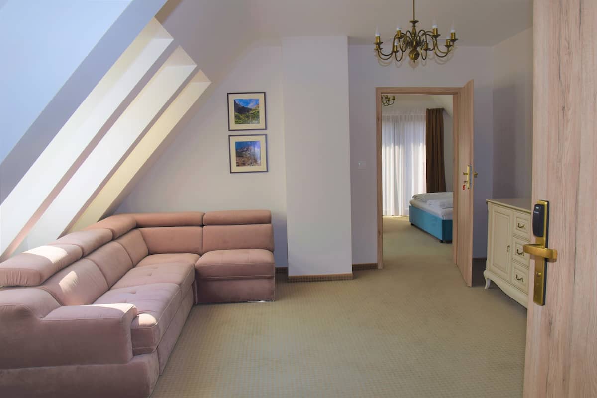Een slaapkamer met een schuine plafond, een groot raam, een bed, een kast en een bank.