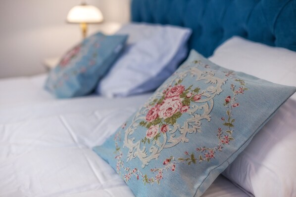 Una cama con ropa de cama blanca y almohadas de estampado floral.