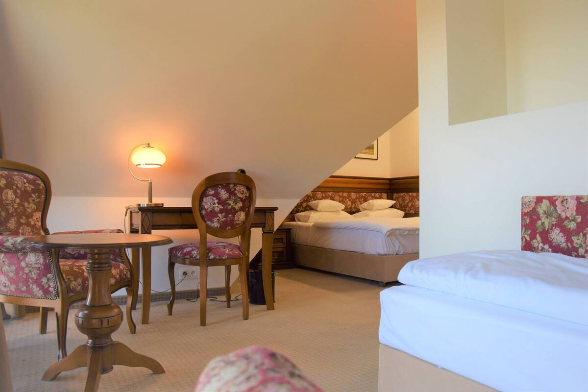 Een slaapkamer met een bed, een bureau, een stoel en een lamp.