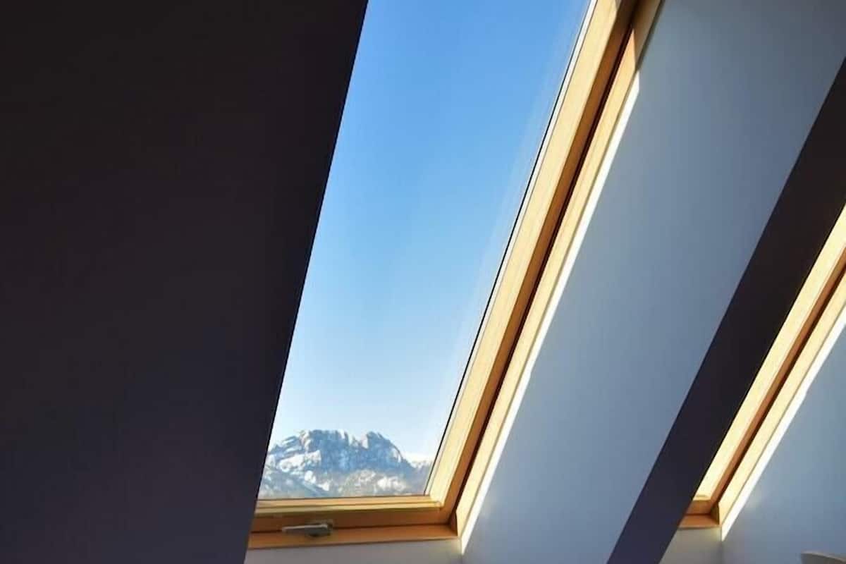 Een slaapkamer met dakraam, een bed en uitzicht op een berg.