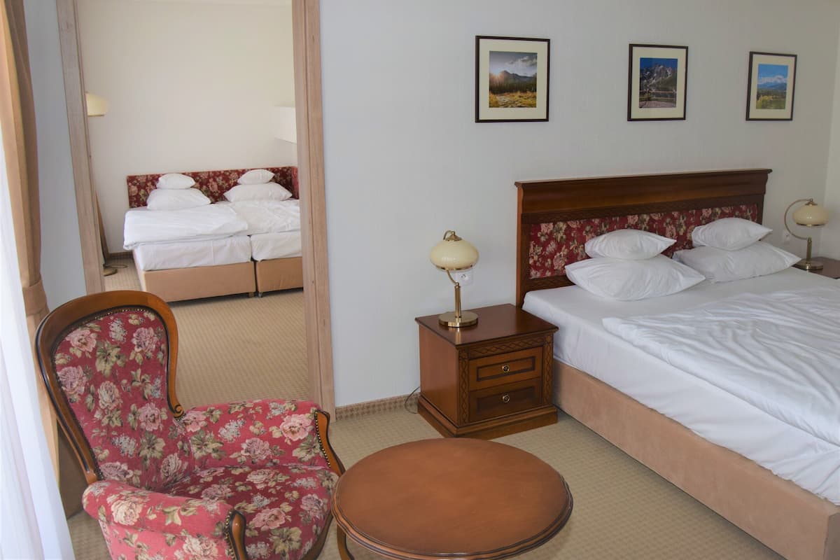 Een hotelkamer met een bed, een stoel, een tafel en drie foto's in lijsten aan de muur.