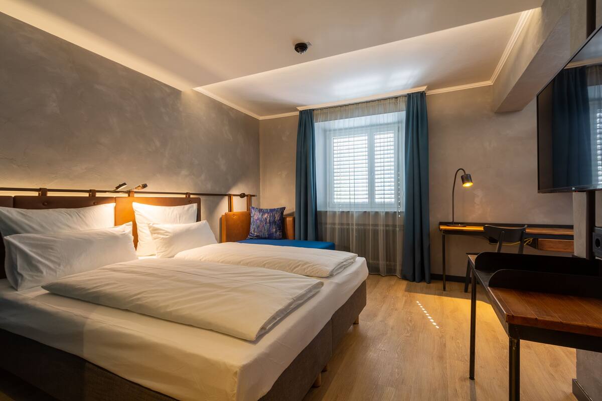 Habitación de hotel con cama, escritorio, silla y televisión.