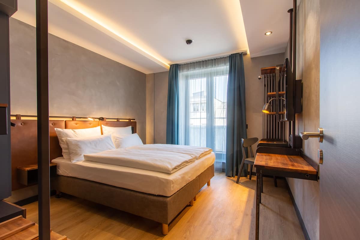 Una habitación de hotel moderna con una cama grande, un escritorio y una silla.