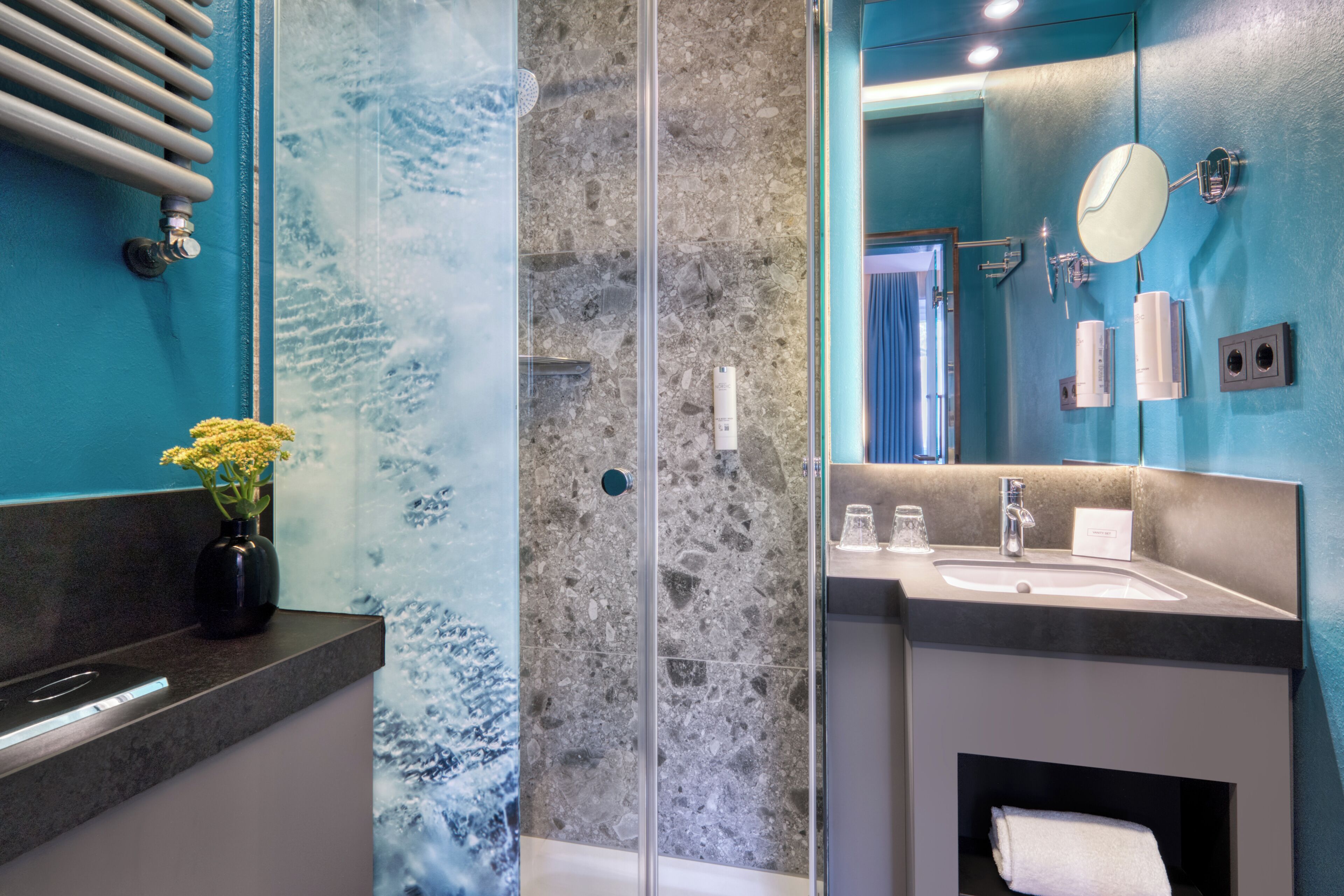 Une salle de bain moderne avec une douche à parois de verre, un lavabo et un miroir.