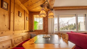 A wooden interior with a dining table, benches, and a red sofa. - Villa Franca UO (Arosa)
