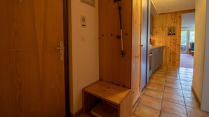 A wooden hallway with a bench, a shower area, and a kitchen visible in the background. - Rothornblick 52 (Arosa)