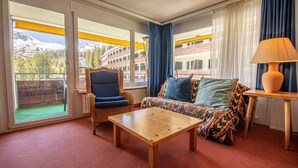 A room with a sofa, armchair, and wooden coffee table. - Rothornblick 52 (Arosa)
