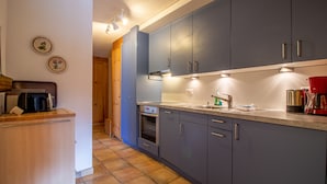 A modern kitchen with grey cabinets, a built-in oven, a coffee maker, and a sink. - Rothornblick 52 (Arosa)
