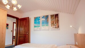 Una camera da letto con un letto, una porta in legno e un'opera d'arte a parete raffigurante una spiaggia.