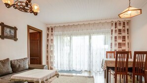 Un accogliente soggiorno con un divano, un tavolo da pranzo con sedie e un lampadario.