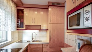 A kitchen with wooden cabinets, a stainless steel sink, a microwave, and a kettle.