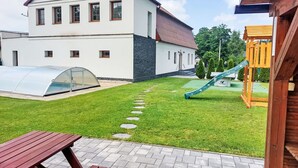 Moderni talo, jossa on suuri puutarha, kasvihuone ja lasten leikkialue.