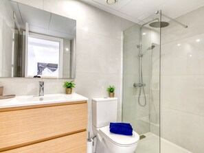 Une salle de bain moderne avec une douche à parois de verre, des toilettes blanches et un meuble-lavabo en bois.