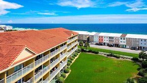 A hotel with a red-tiled roof, multiple balconies, and a view of the ocean. - Ciboney Beach Resort Panhandle Getaways (Miramar Beach)