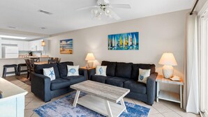 A modern living room with a sofa set, a coffee table, and a painting of sailboats on the wall. - Ciboney Beach Resort Panhandle Getaways (Miramar Beach)