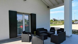 An outdoor patio with wicker furniture, a glass door, and a view of a rural landscape. - Wonderful private villa for 6 guests with A/C, pool, WIFI, TV and balcony (Venice)