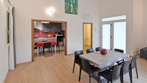 A modern dining area with a large table and chairs, a kitchen in the background, and a painting on the wall. - Wonderful private villa for 6 guests with A/C, pool, WIFI, TV and balcony (Venice)