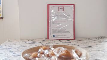 Ein gerahmtes Willkommen-Schild mit Kontaktinformationen und einer Website-URL, eine Schüssel mit Essen auf einem Tisch mit gemustertem Tischläufer.
