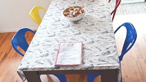 Una mesa de comedor con un mantel estampado, un plato de comida y un menú sobre la mesa.