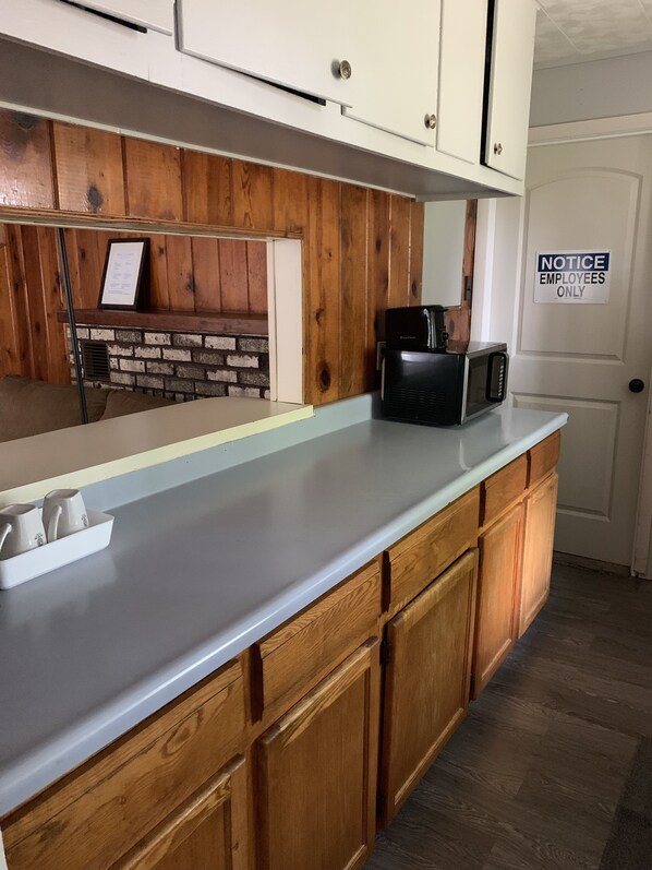 A kitchen with wooden cabinets, a white countertop, a microwave, and a notice on the door.