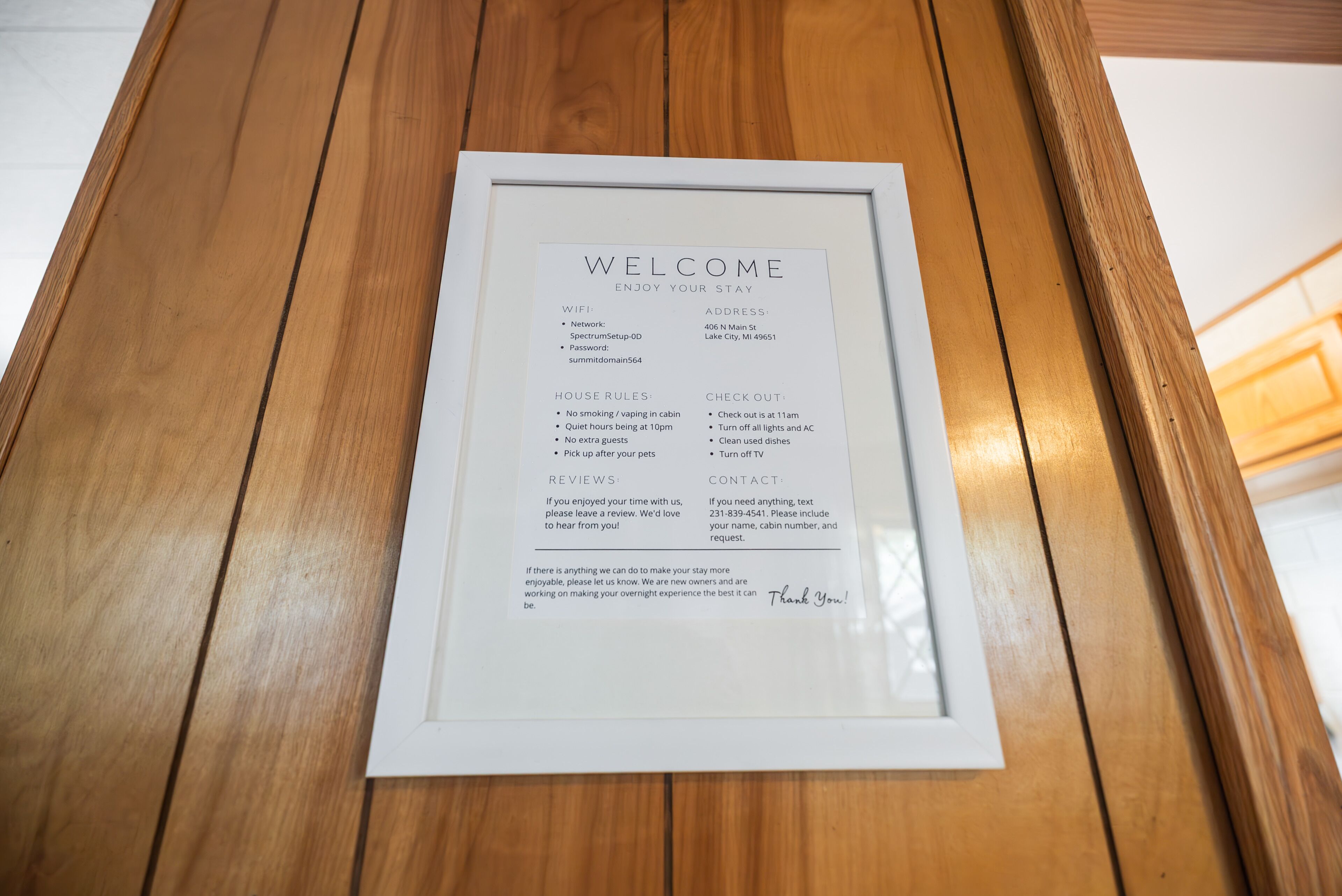A framed welcome sign with house rules, WiFi details, and contact information for a hotel.