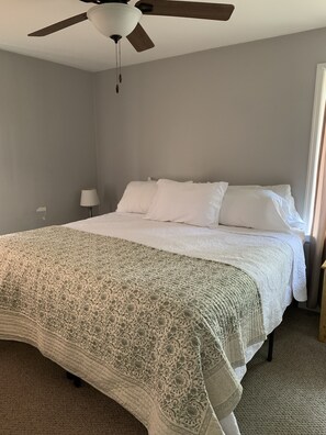 A bedroom with a bed, a ceiling fan, and a window.