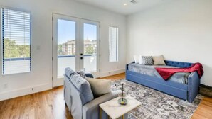Un salon spacieux avec un canapé bleu, un divan gris et un tapis à motifs.