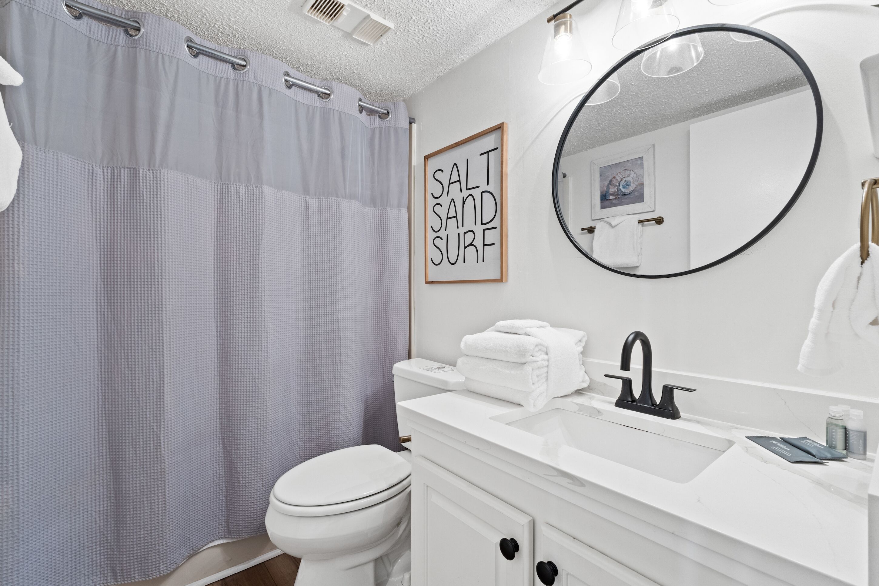 A bathroom with a toilet, sink, and shower curtain.