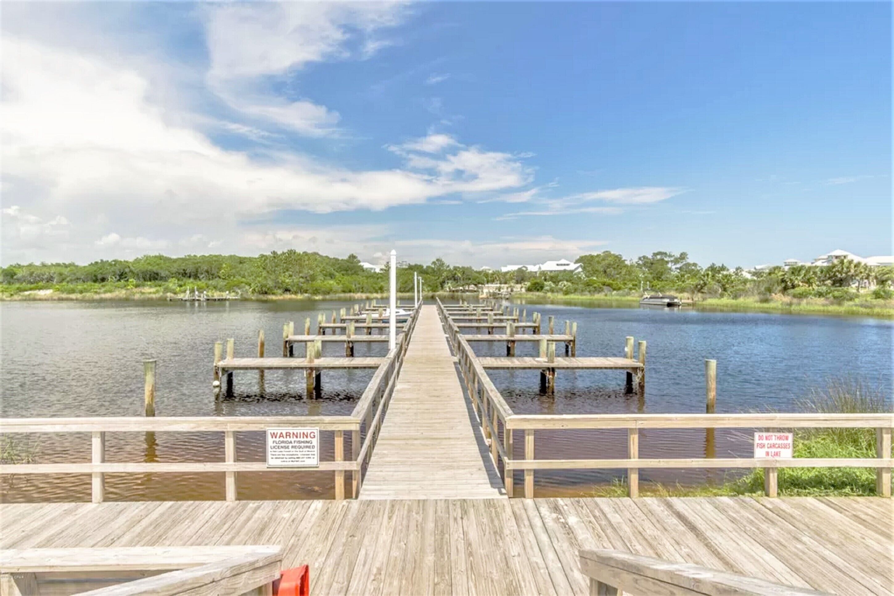 A wooden pier extending into a calm body of water with a clear sky above.