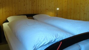 A room with two single beds, wooden walls, and a small bedside table with a lamp. - Lovely apartment for 4 people with balcony (Lenk)