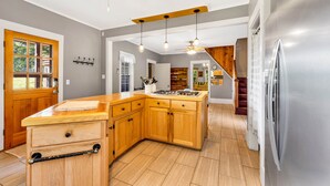 Una cocina moderna con armarios de madera, un refrigerador de acero inoxidable y una encimera de madera.