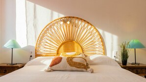 A bed with a woven headboard, two bedside lamps, and a potted plant. - Cosy apartment for 4 guests with WIFI, A/C, TV and terrace (Torredembarra)